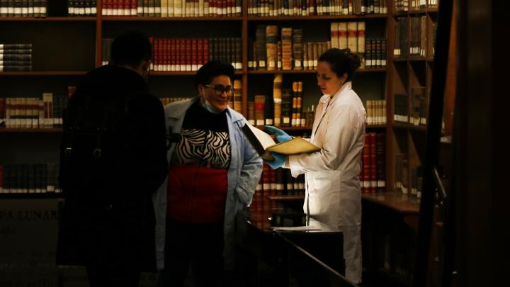 Las expositoras y autoras de la investigación revisando un libro en la Biblioteca